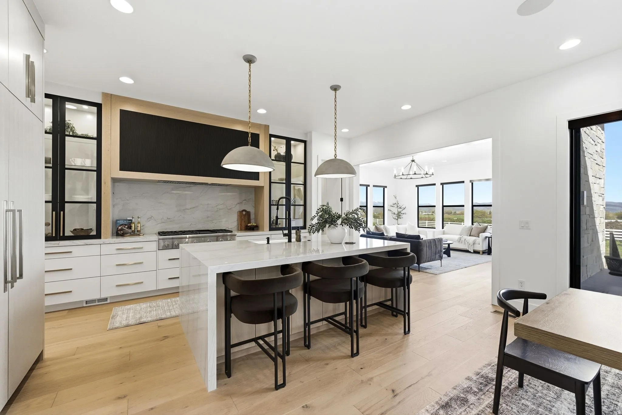 Gourmet kitchen featuring a waterfall island, light wood-finish flooring, white cabinetry, a large range with a stone backsplash, and recessed lighting