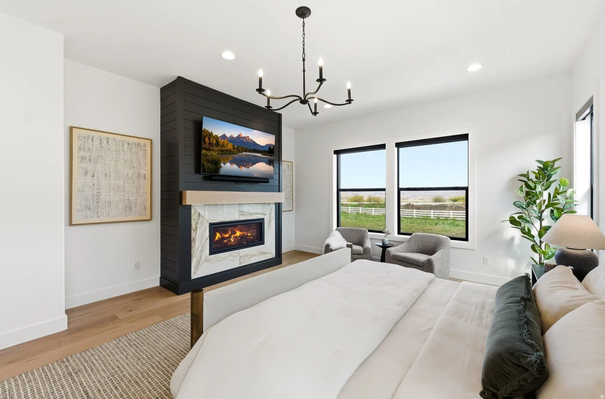 Spacious room featuring a contemporary fireplace with a stone surround, a prominent flat-screen television, and multiple large windows