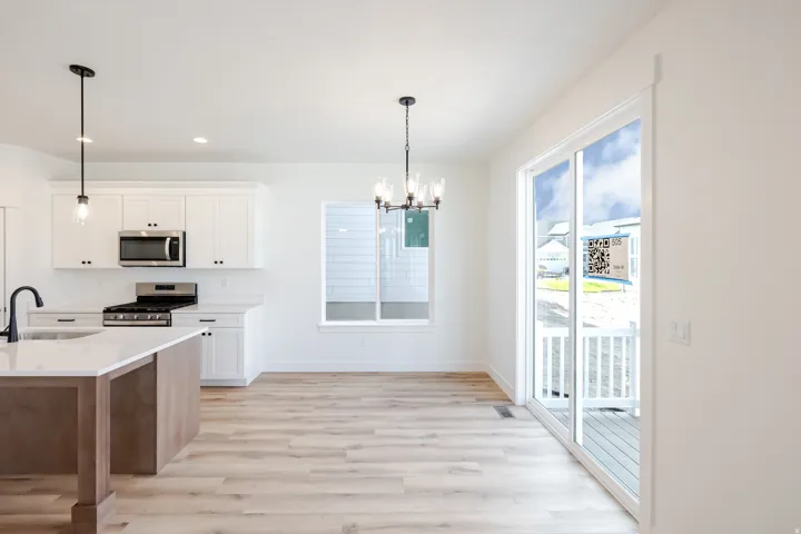 Kitchen featuring white cabinetry, stainless steel appliances, a wood-finish island with a white countertop, and wood-finish flooring
