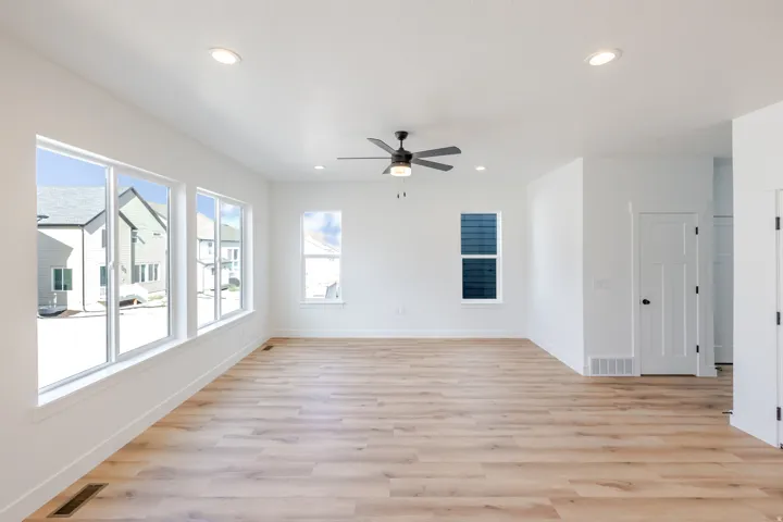 Expansive living area featuring light wood-finish flooring, recessed lighting, and a contemporary ceiling fan