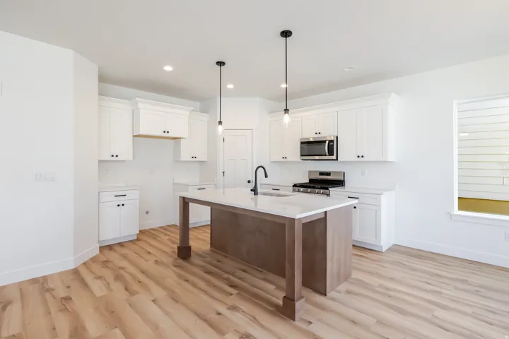 Modern kitchen with wood-finish flooring, white cabinetry, a kitchen island with pendant lighting, stainless steel appliances, and solid surface countertops