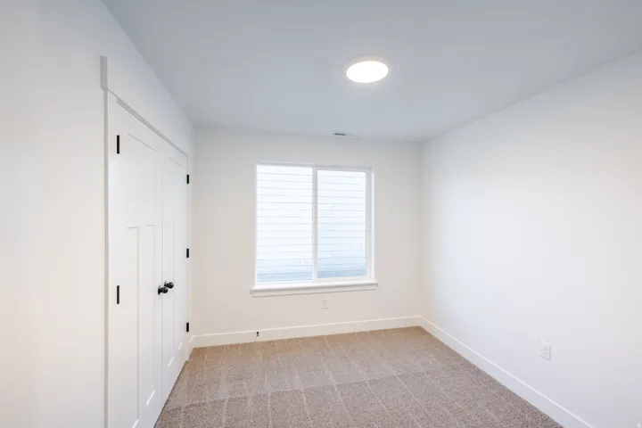 Recessed ceiling light, neutral carpeting, white window blinds, white wall finish, and white trim
