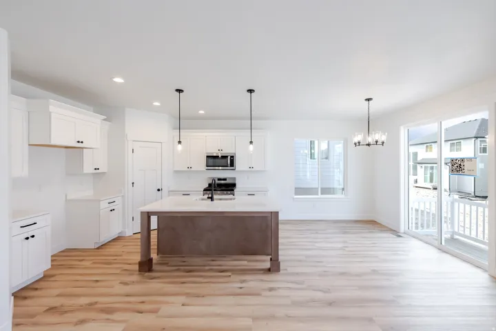 Bright kitchen with white cabinetry, wood-finish flooring, a central island, and stainless steel appliances