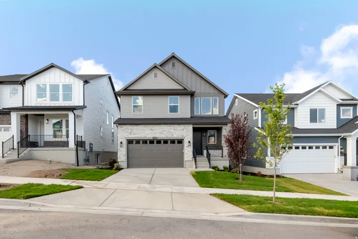 Contemporary style residence featuring a two-car garage, stone veneer and siding facade, covered front entry, and concrete driveway
