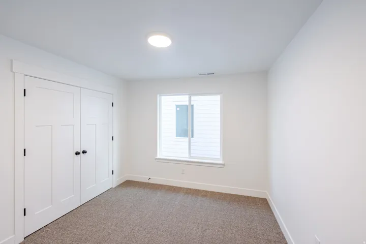 Recessed window with white trim, two white paneled doors with matte black hardware, and an overhead flush-mount light fixture