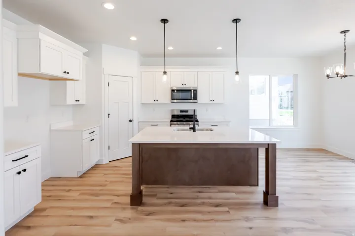 Kitchen featuring white cabinetry, a center island with a light-toned countertop, stainless steel appliances, wood-finish flooring, and recessed lighting