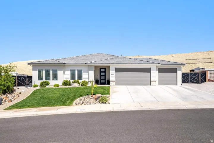 Contemporary single-story residence featuring a light-colored stucco and siding exterior, a multi-car concrete driveway, and a low-pitched shingled roof