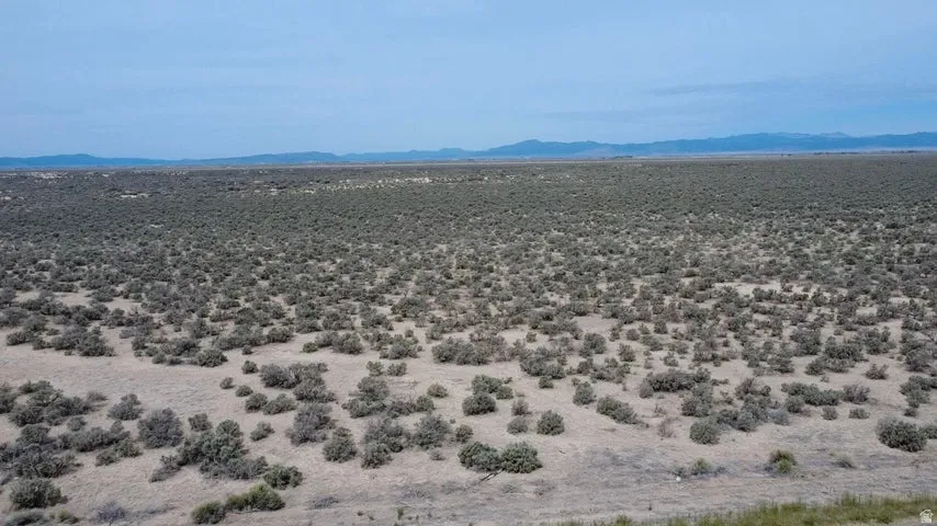 Expansive land parcel with natural scrub brush and distant mountain ranges under a clear sky