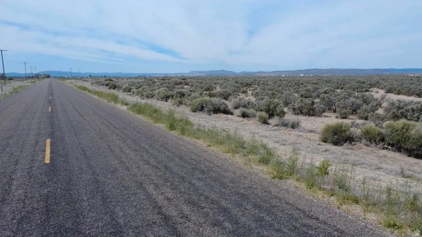 Paved road bordering an expansive land parcel featuring natural desert vegetation