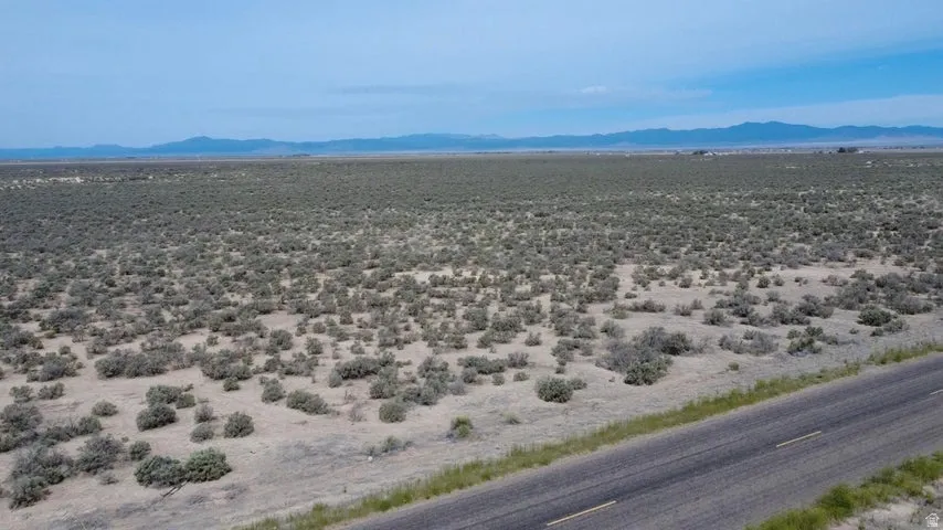 Expansive open land featuring natural vegetation and a distant mountain range backdrop