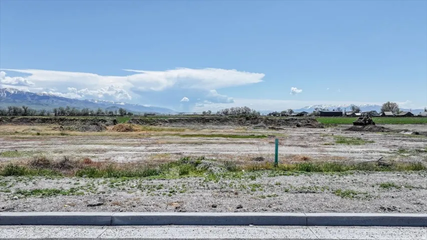 Expansive land parcel featuring distant snow-capped mountain scenery, a partially cleared landscape, and visible utility infrastructure