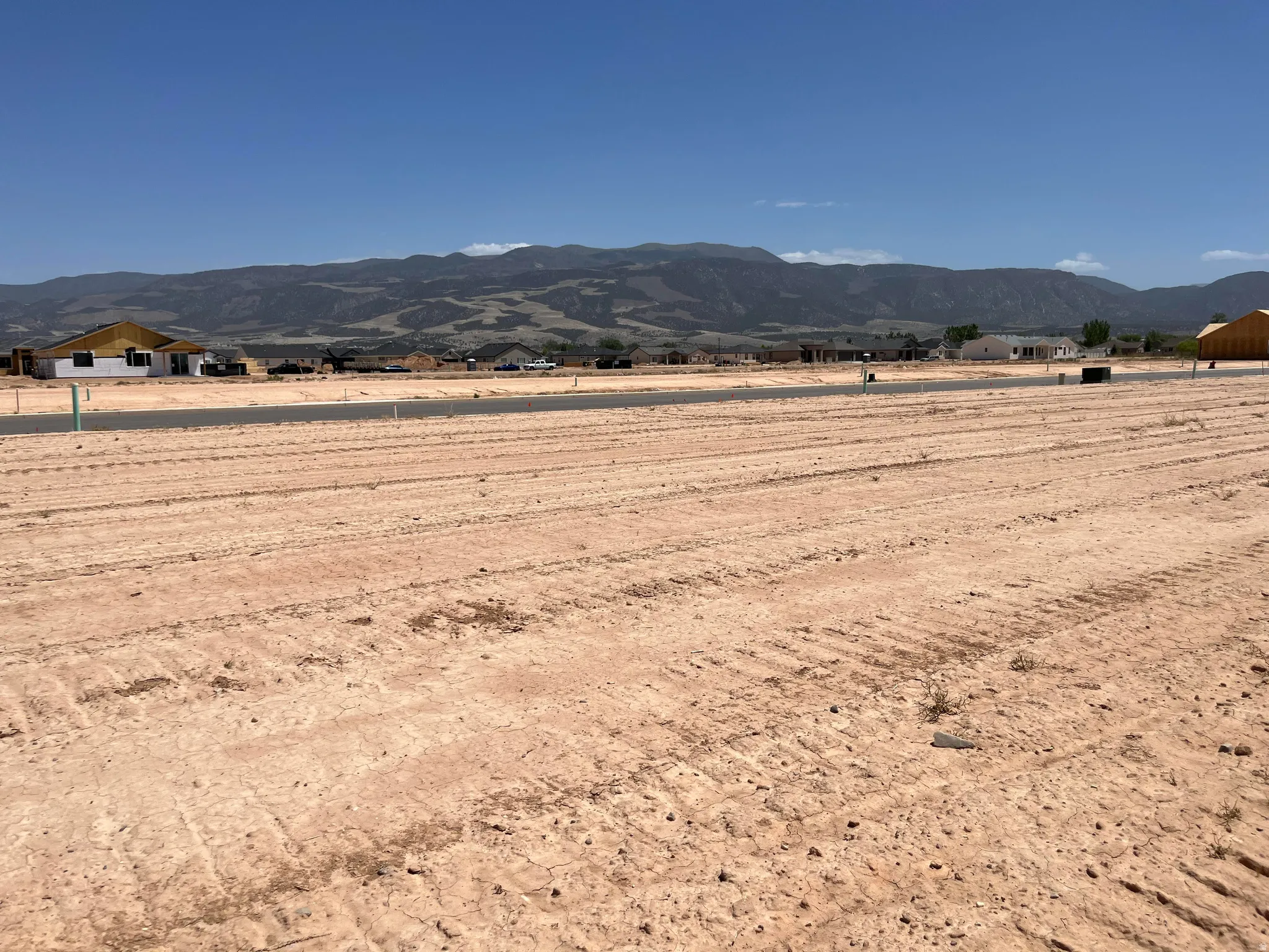 Expansive vacant lot featuring a cleared, level surface and distant mountain backdrop