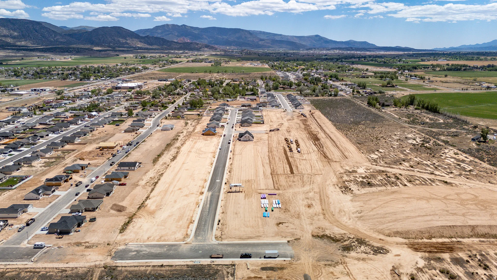 Expansive aerial captures a developing residential community featuring numerous completed homes, new road infrastructure, and available building lots