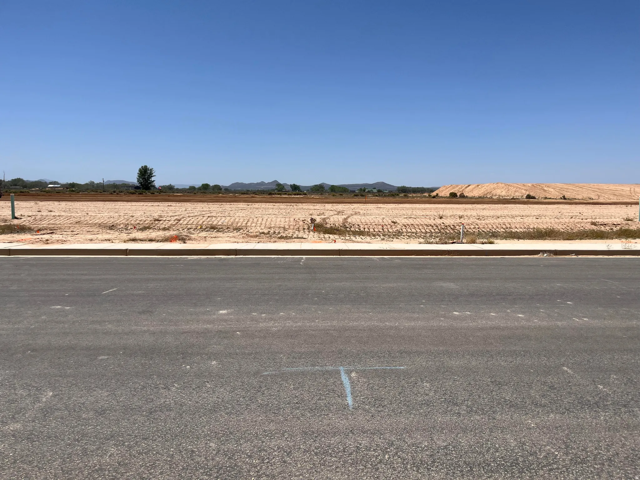 Vacant land parcel featuring an expansive, level terrain with visible mountain range in the distance and clear blue skies