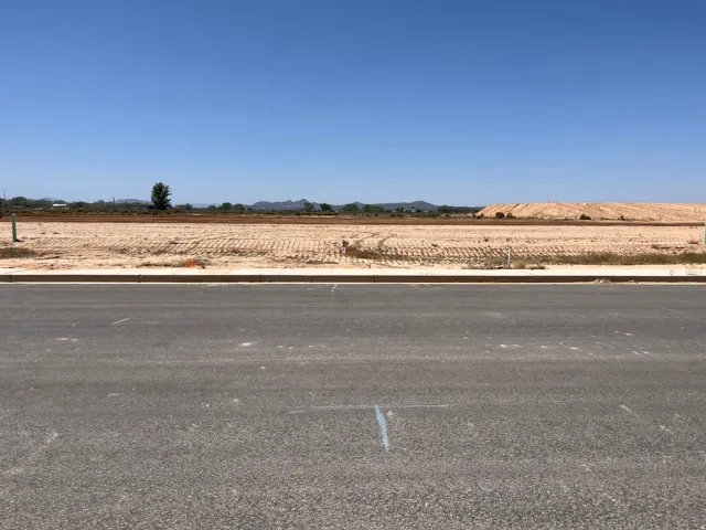 Vacant land parcel featuring an expansive, level terrain with visible mountain range in the distance and clear blue skies