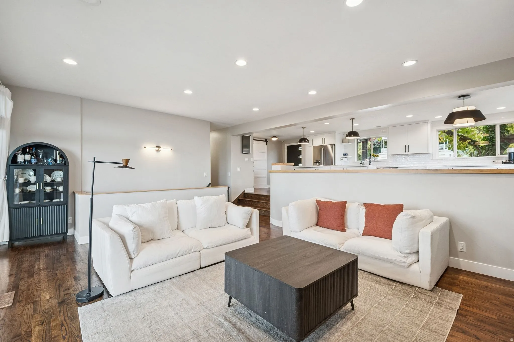 Open-concept living area with wood-finish flooring, recessed lighting, and a partial wall separating spaces