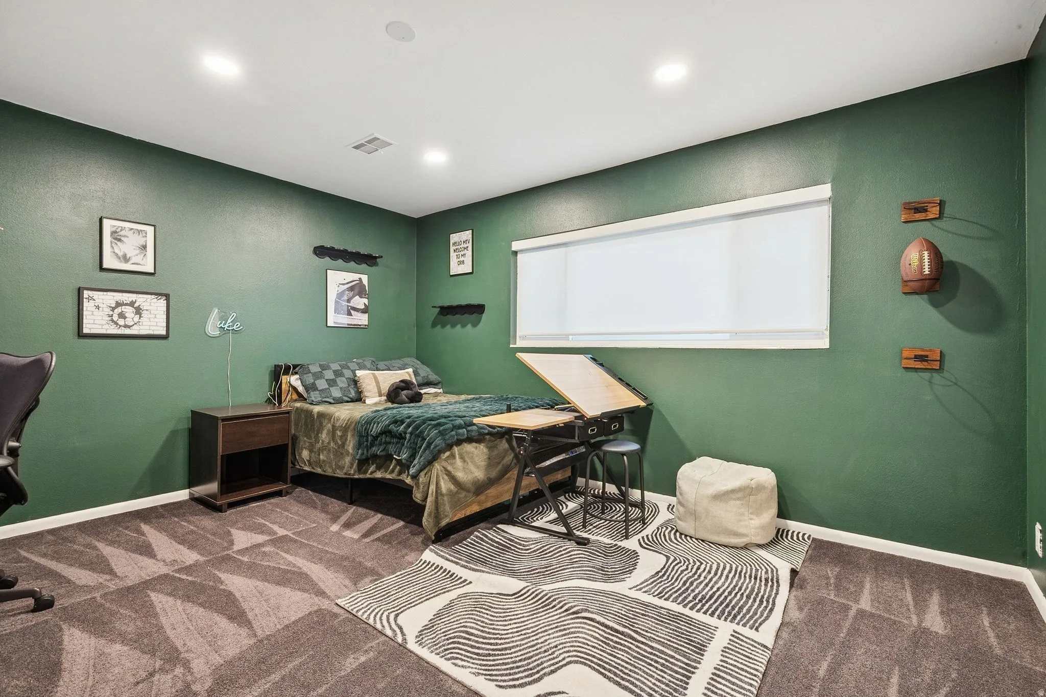 Carpeted room featuring recessed lighting, a window with a roller shade, and a built-in wall shelf