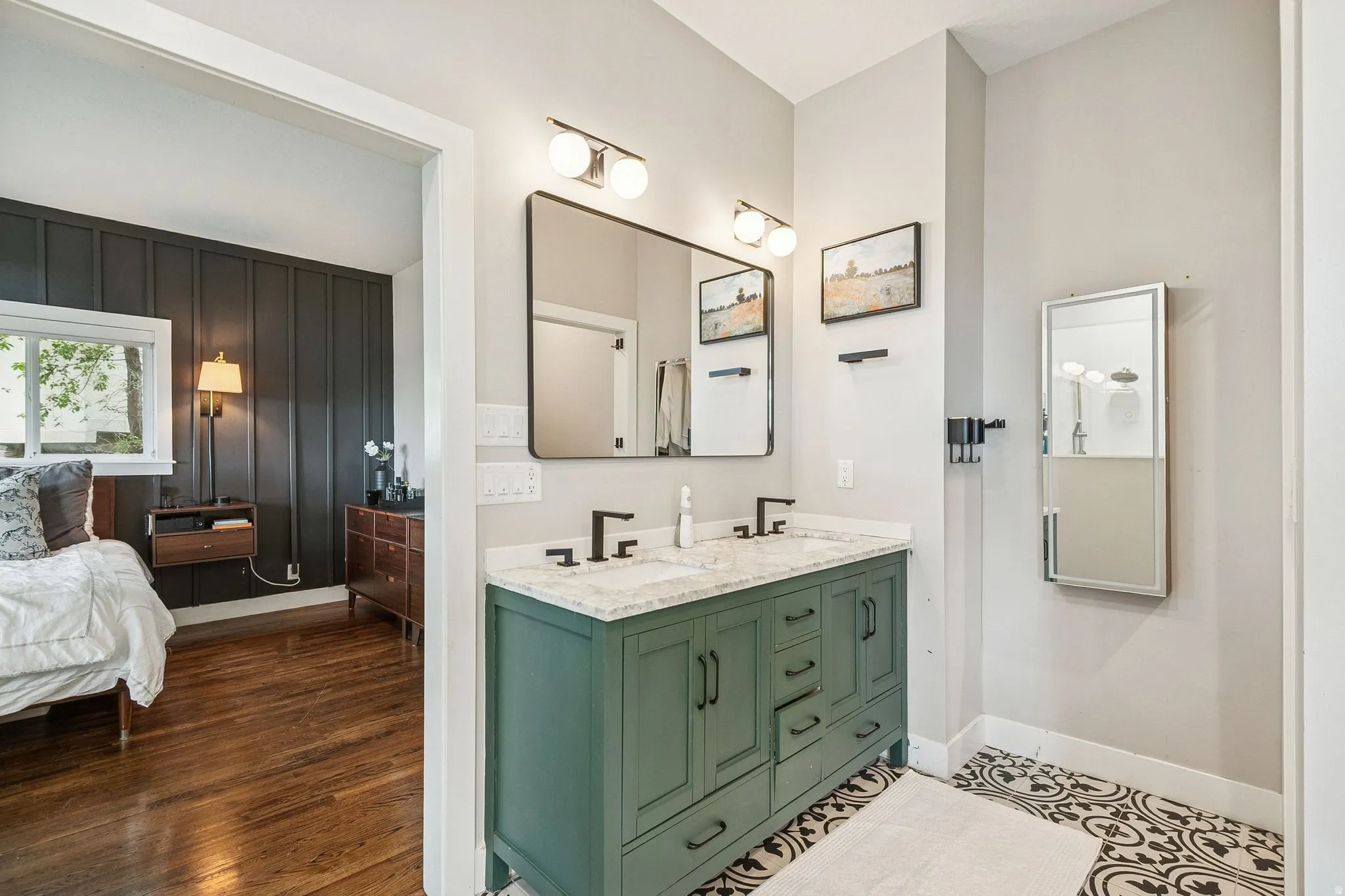 Bathroom vanity with dual sinks, a solid surface countertop, matte black fixtures, and a decorative tile floor
