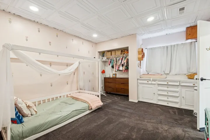 Recessed lighting illuminates the textured ceiling paneling and soft patterned wallpaper