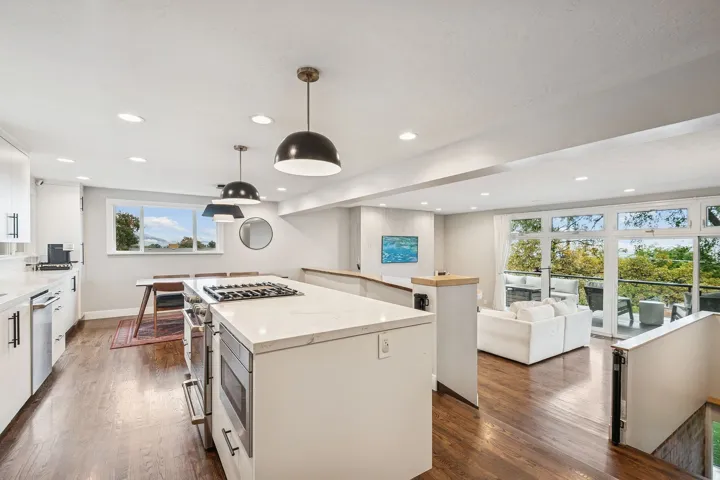 Open-concept kitchen featuring an island with a gas cooktop, white cabinetry, integrated appliances, and recessed lighting