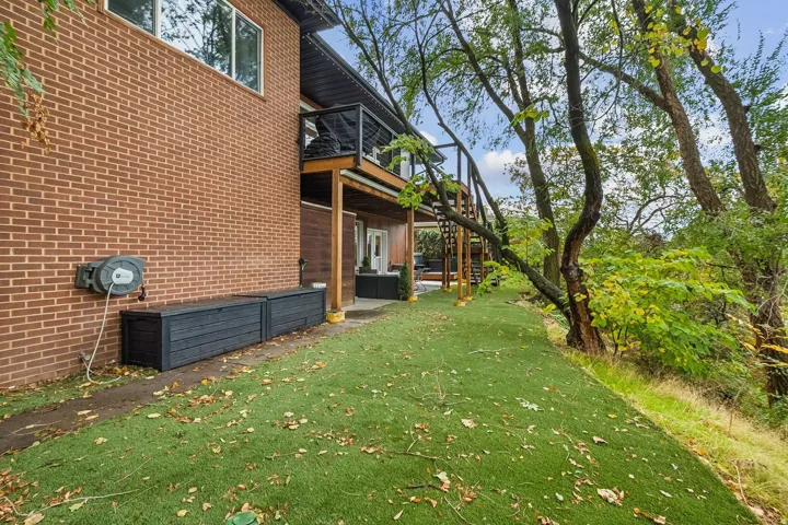 Terraced landscaping with artificial turf, bordered by mature trees and natural foliage