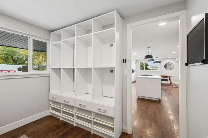 Custom built-in white shelving and drawers with gold-tone hardware, providing extensive storage