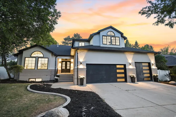 Modern stucco exterior featuring a two-car garage with contemporary glass-paneled doors, arched windows, and a concrete driveway