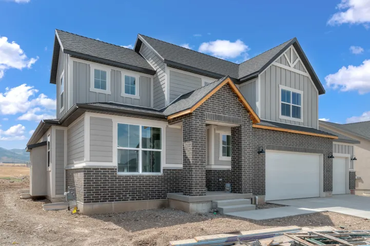 Modern two-story residence featuring a striking mixed-material exterior with dark brick and light gray fiber cement siding accented by wood-tone trim