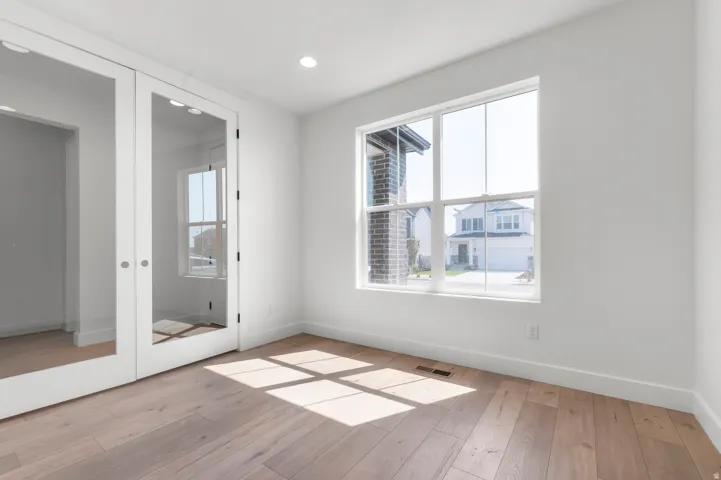 Wood-finish flooring, recessed lighting, and a large window with white trim