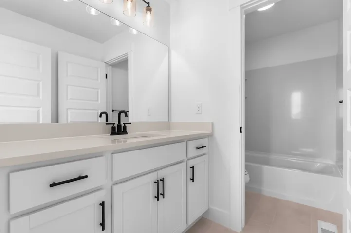 Vanity with light-colored countertop, undermount sink, and matte black fixtures