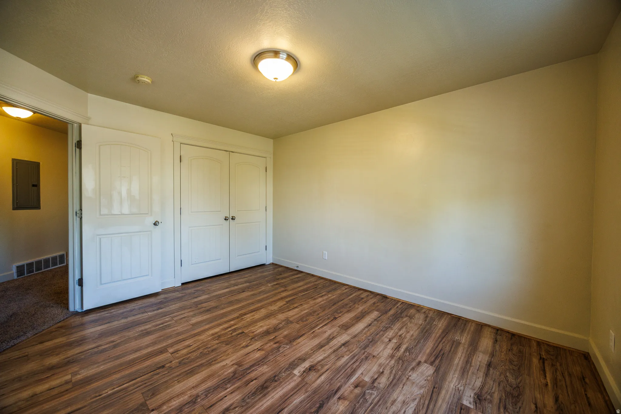 Room featuring wood-finish flooring, neutral wall tones, and white baseboards