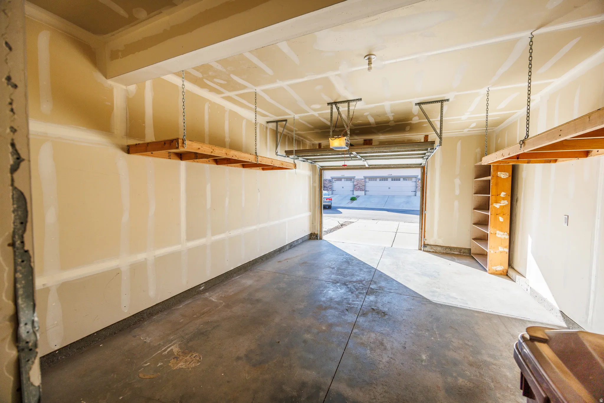 Spacious garage featuring a concrete floor, overhead storage racks, built-in shelving, and an automatic garage door opener
