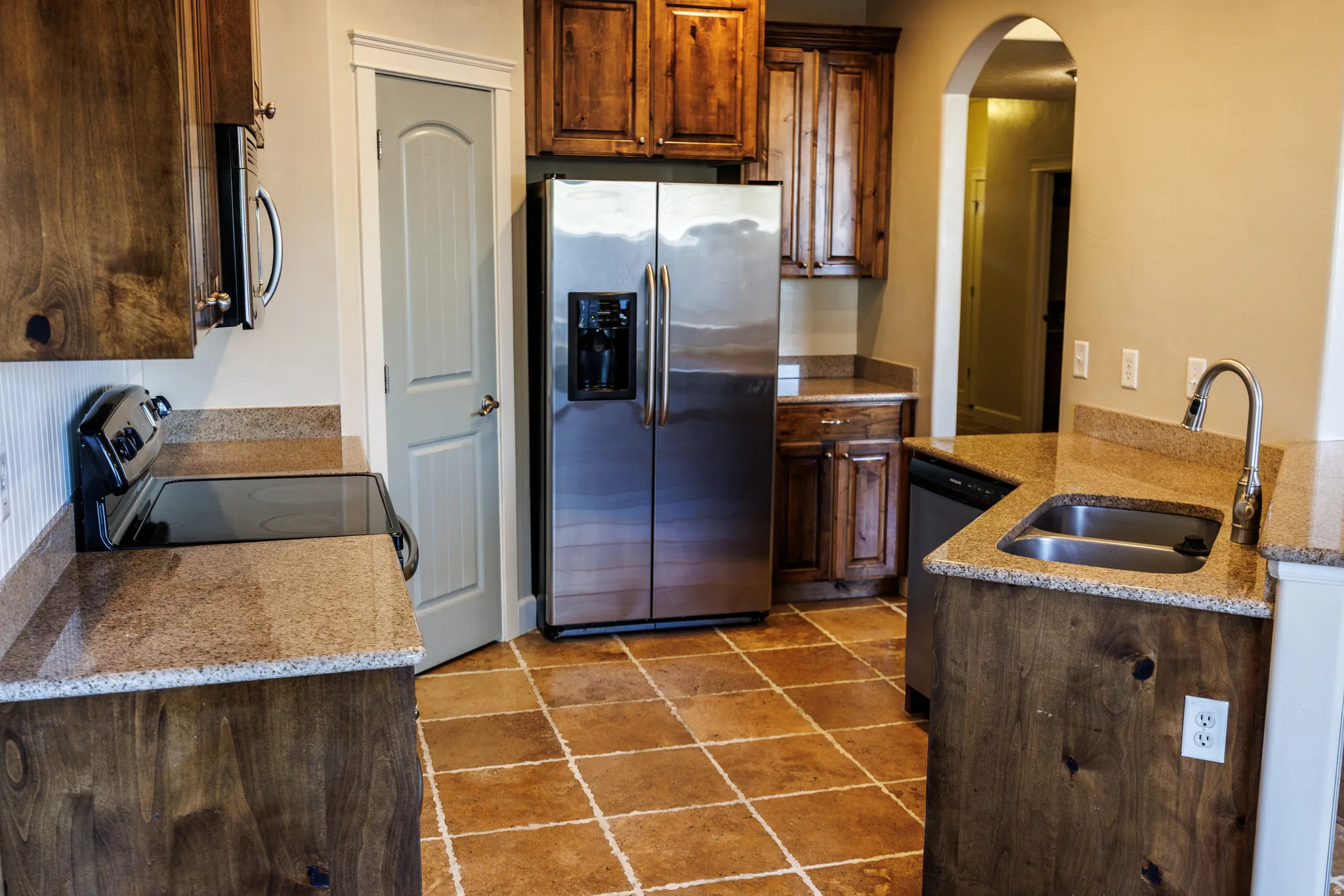 Kitchen featuring wood-finish cabinetry, stainless steel appliances, and stone countertops