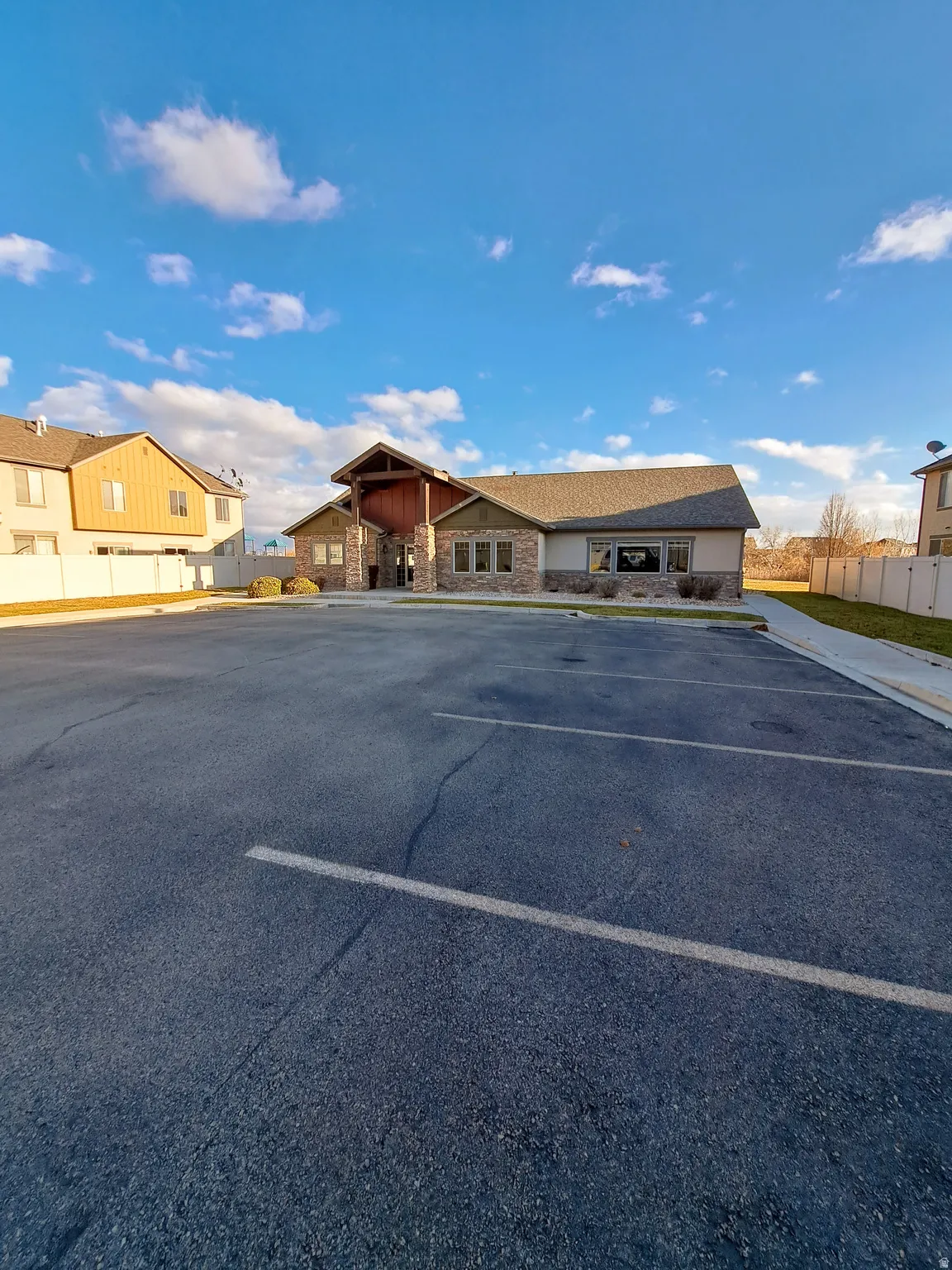 Exterior building featuring stone veneer accents, horizontal siding, multiple windows, and a prominent covered entry