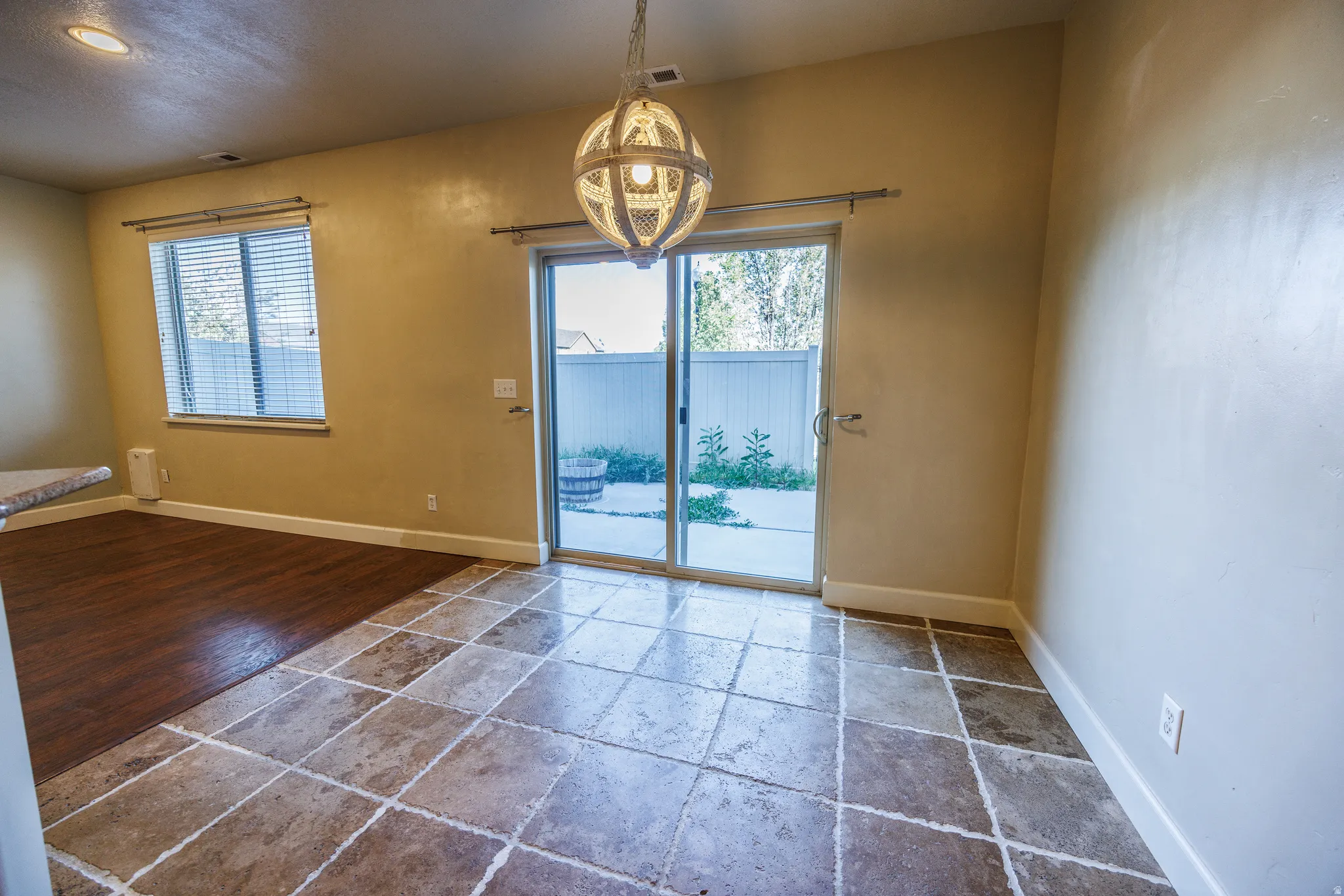 Tiled flooring with an adjacent wood-finish floor section, featuring a hanging spherical light fixture