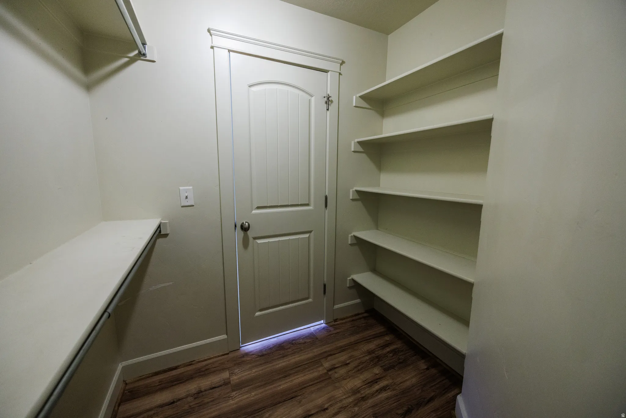 Dedicated storage space featuring wood-finish flooring, built-in shelving, and a clothing rod