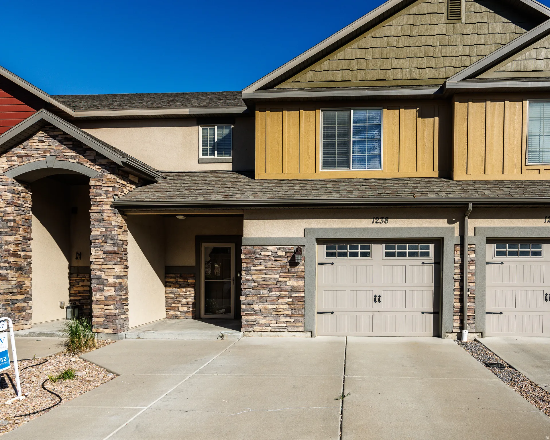 Multi-level exterior featuring varied siding materials including stucco, wood-finish paneling, and stacked stone accents