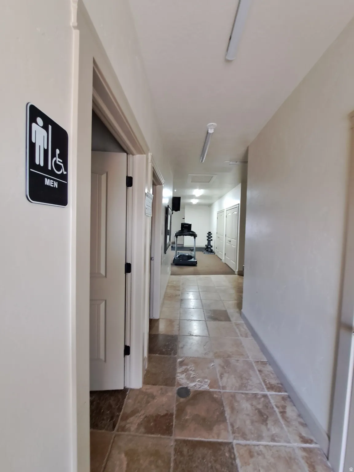 Hallway featuring square tile flooring and multiple white paneled doors