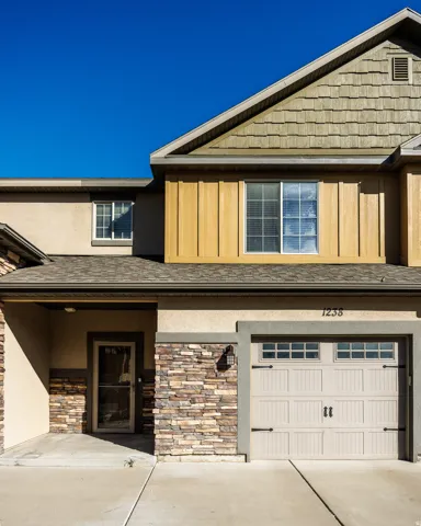 Two-story residence featuring a combination of stucco, stacked stone, and vertical wood paneling