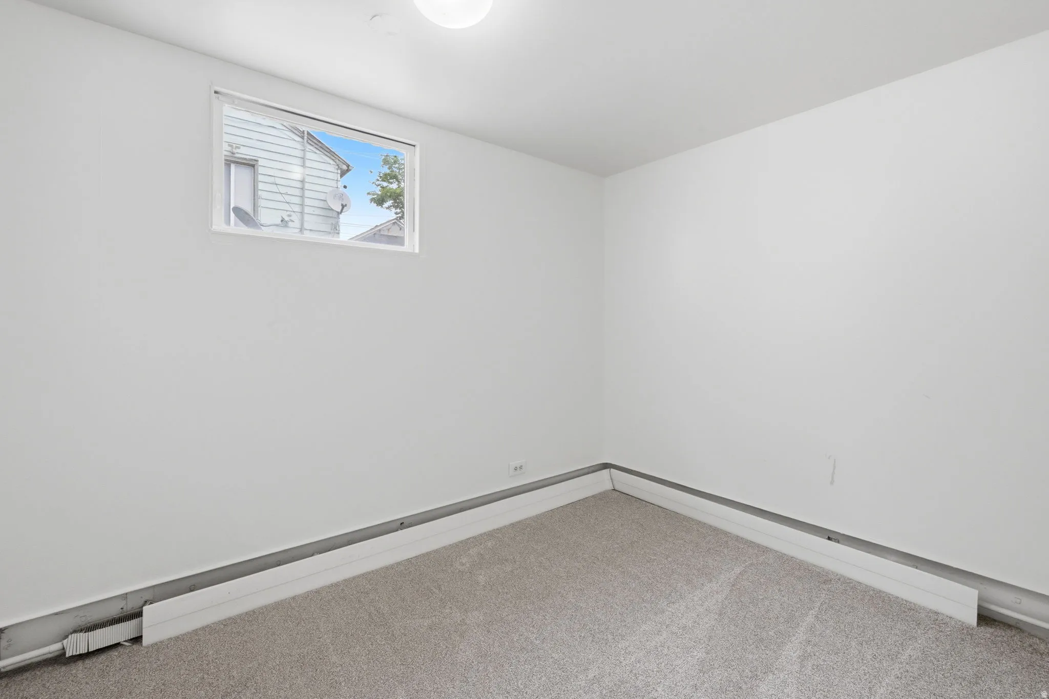 Neutral wall finishes, a single window, and light-colored carpeting