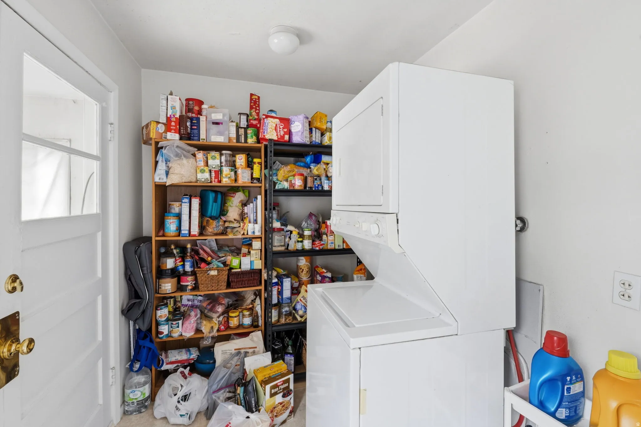 Laundry area featuring a stacked washer and dryer, adjacent to built-in shelving and a white paneled door