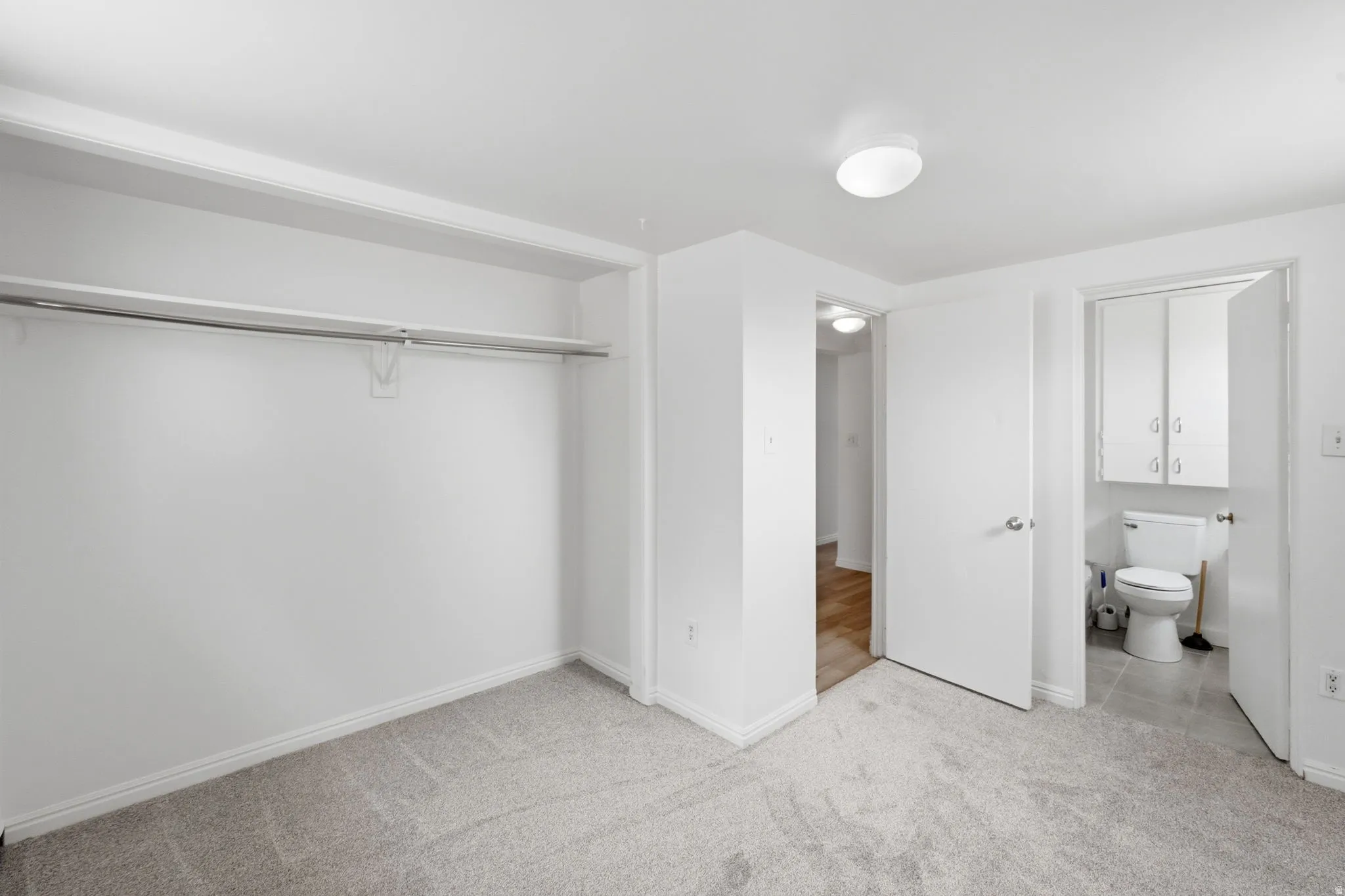 Carpeted room featuring a built-in closet with hanging rod and shelving