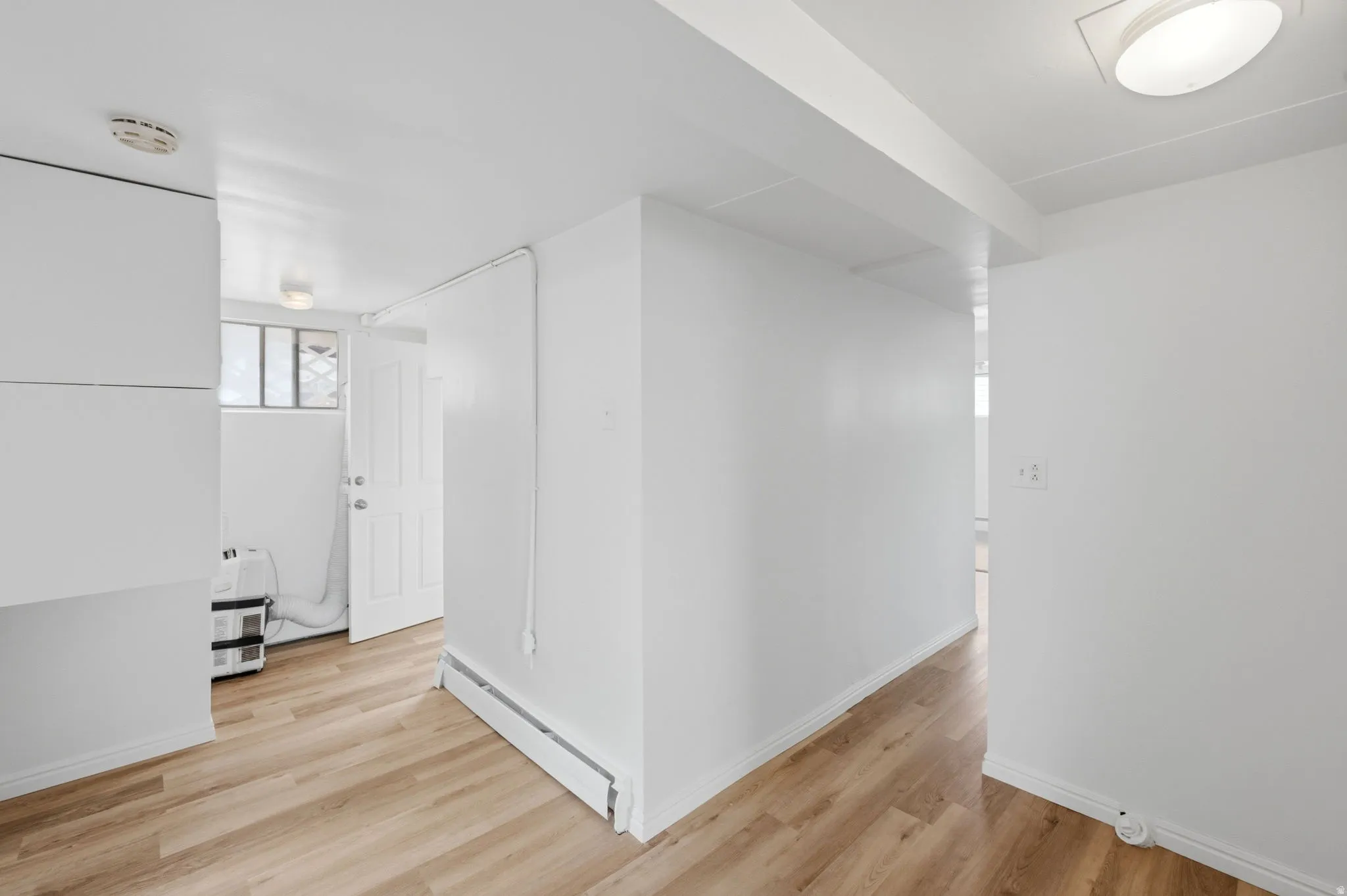 Bright interior space featuring wood-finish flooring, white walls, and flush-mount ceiling lighting