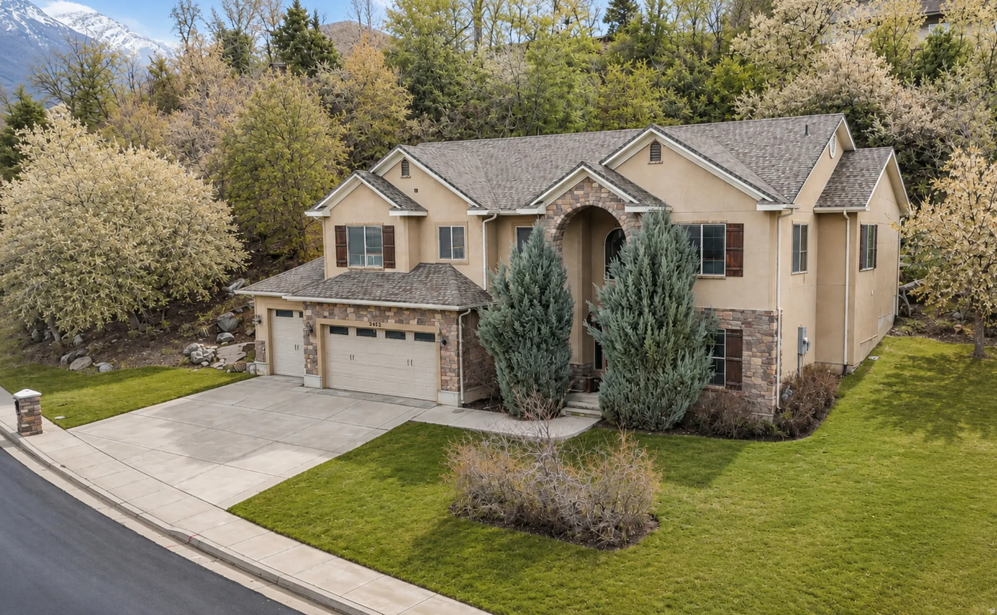 Stucco and stone exterior featuring multiple gables and a two-car garage