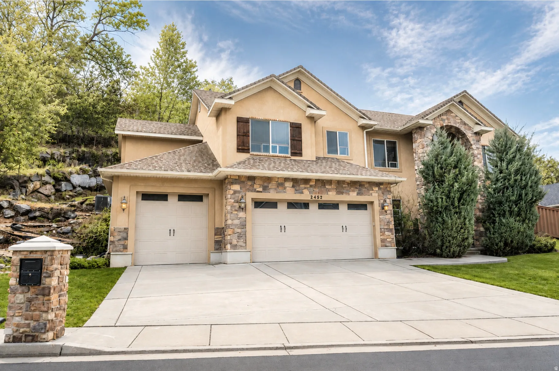 Stucco and stone exterior featuring multiple gables and a prominent arched entry