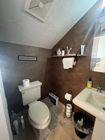 Pedestal sink with chrome faucet and mirror, complemented by a white toilet