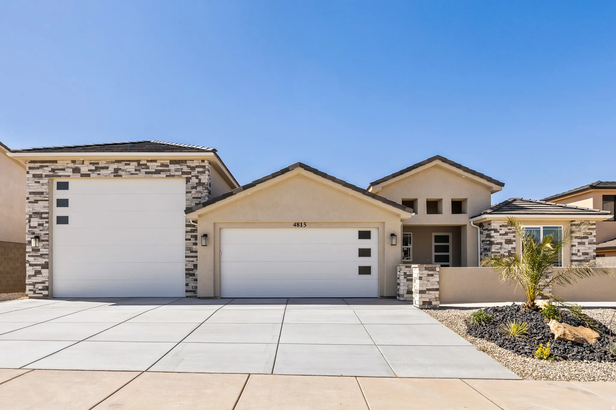 Contemporary facade featuring a light stucco finish and stacked stone accents