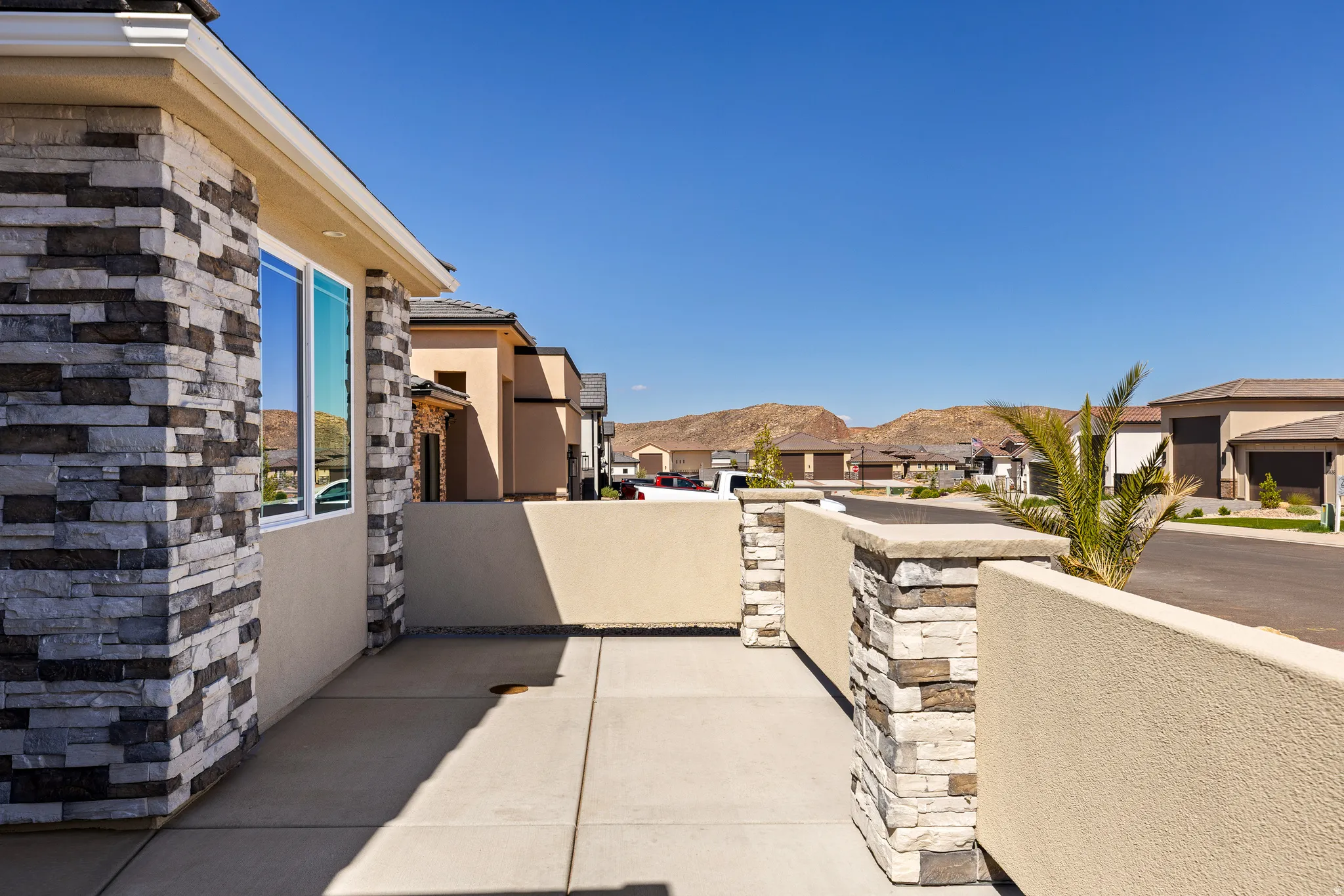 Exterior stone veneer siding and stucco finish with a concrete walkway
