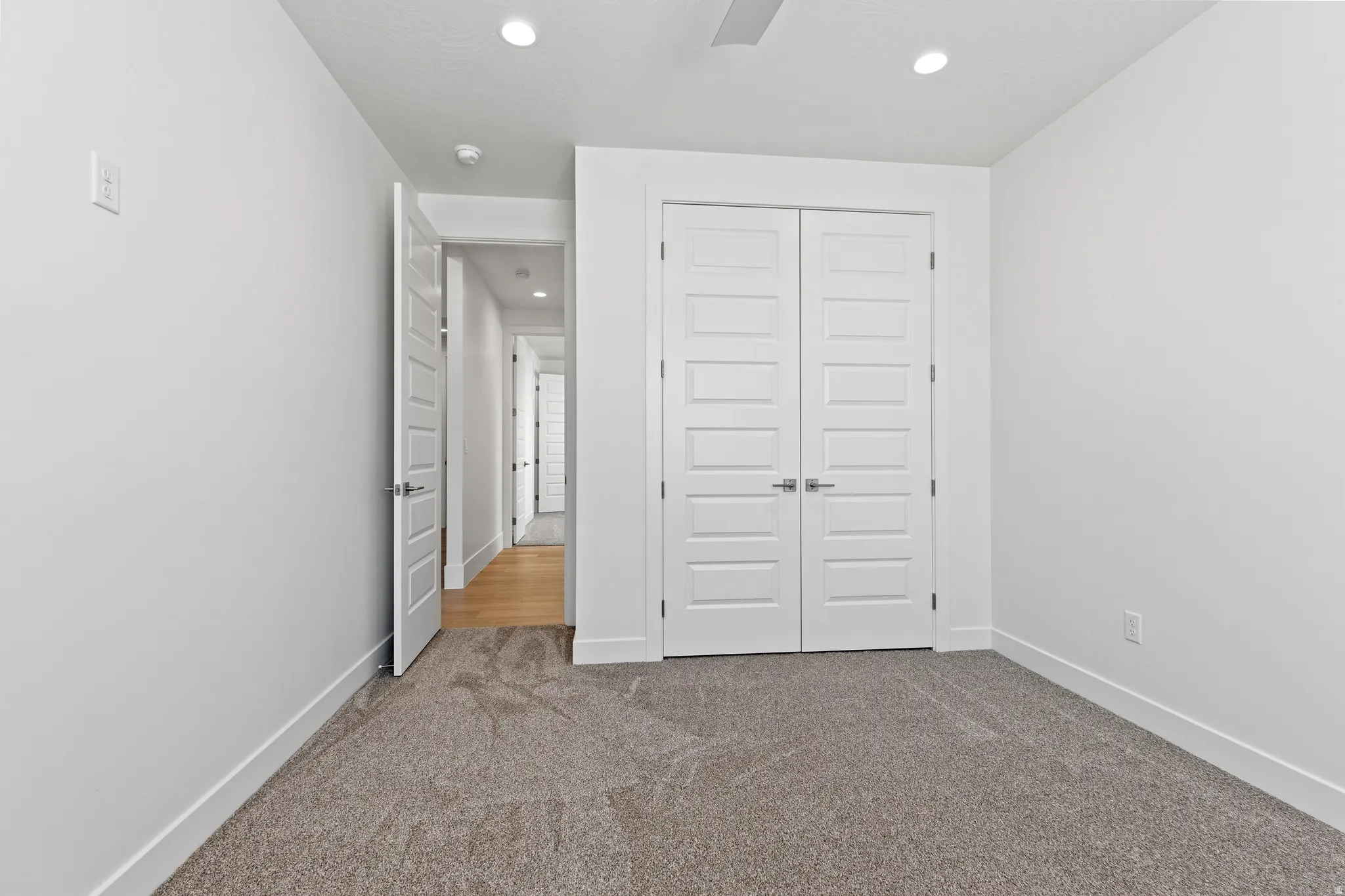 Neutral tone wall finishes with wide white baseboards and gray textured carpet