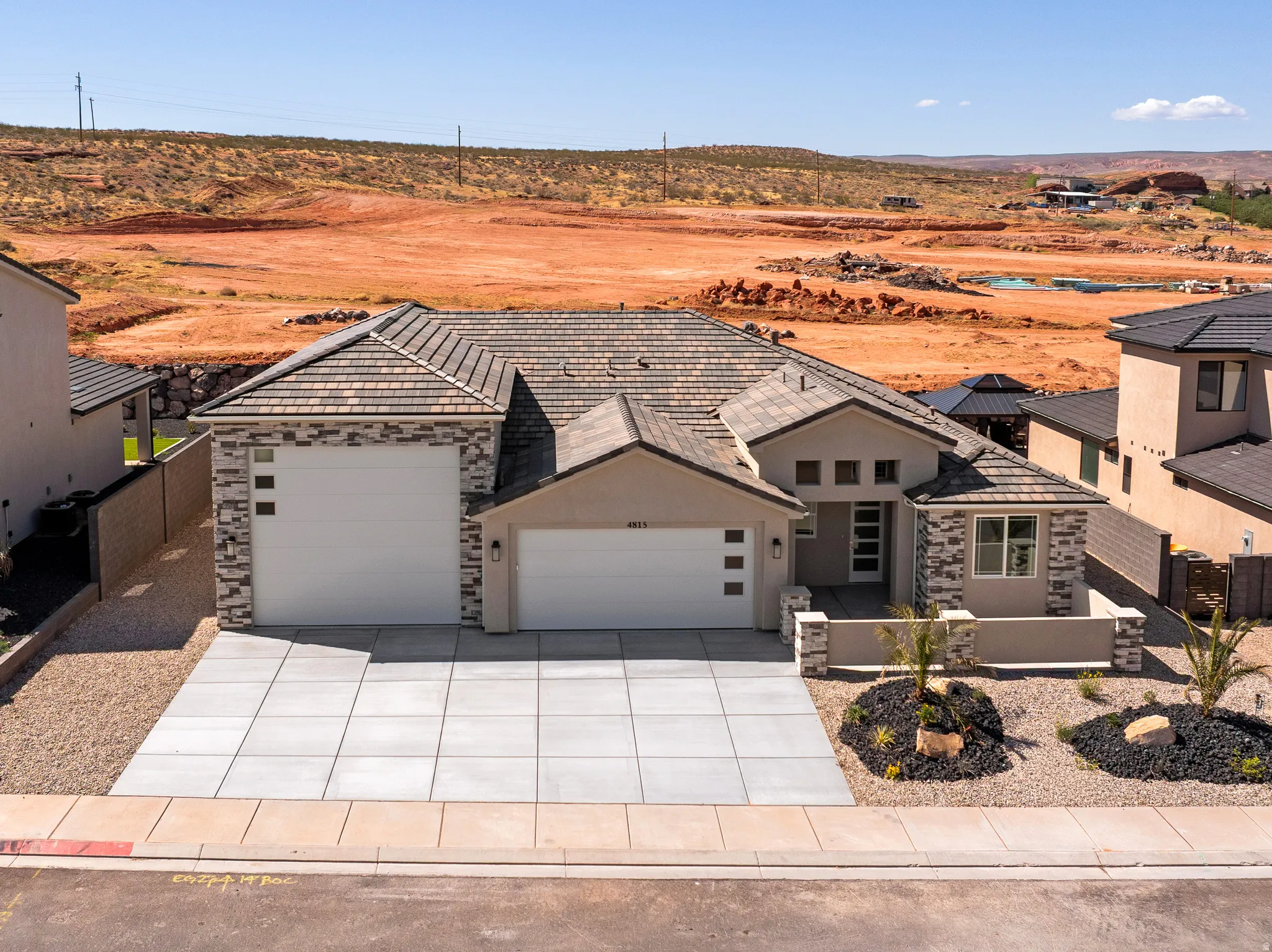 Modern stucco and stone facade residence featuring a multi-car garage, concrete driveway, and low-maintenance landscaping